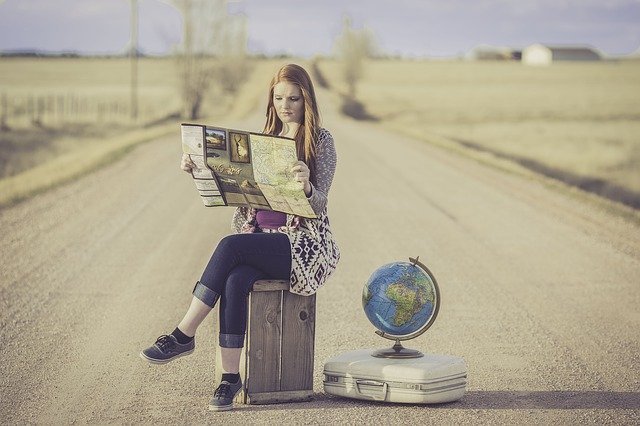 Woman Sitting on Suitcase Reading Map